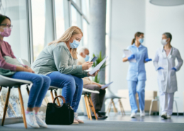 Woman with face mask using smart phone while reading her medical report in waiting room at the clinic.