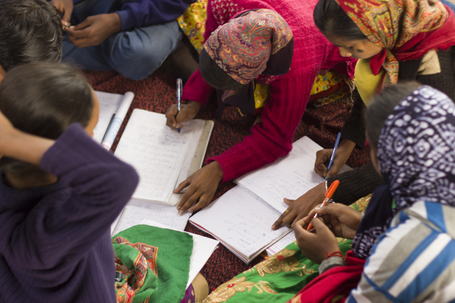 Girls in Indian village school study in a cirlcle, wearing head scarves